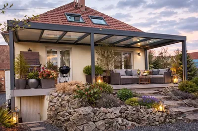 Avant / après d’une pergola aluminium avec puits de lumière, stores de façade et latéral installée à Laubach pour remplacer un store banne.