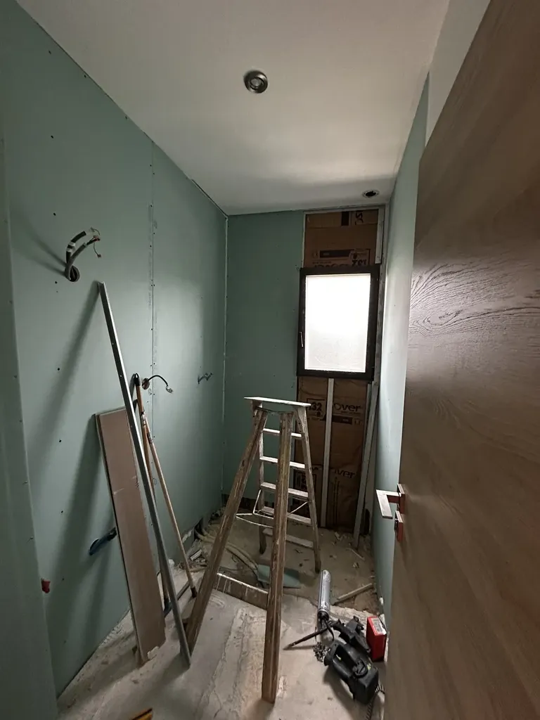 Pose de plaques de plâtre hydrofuges (BA13) dans une salle de bain en rénovation après dégât des eaux