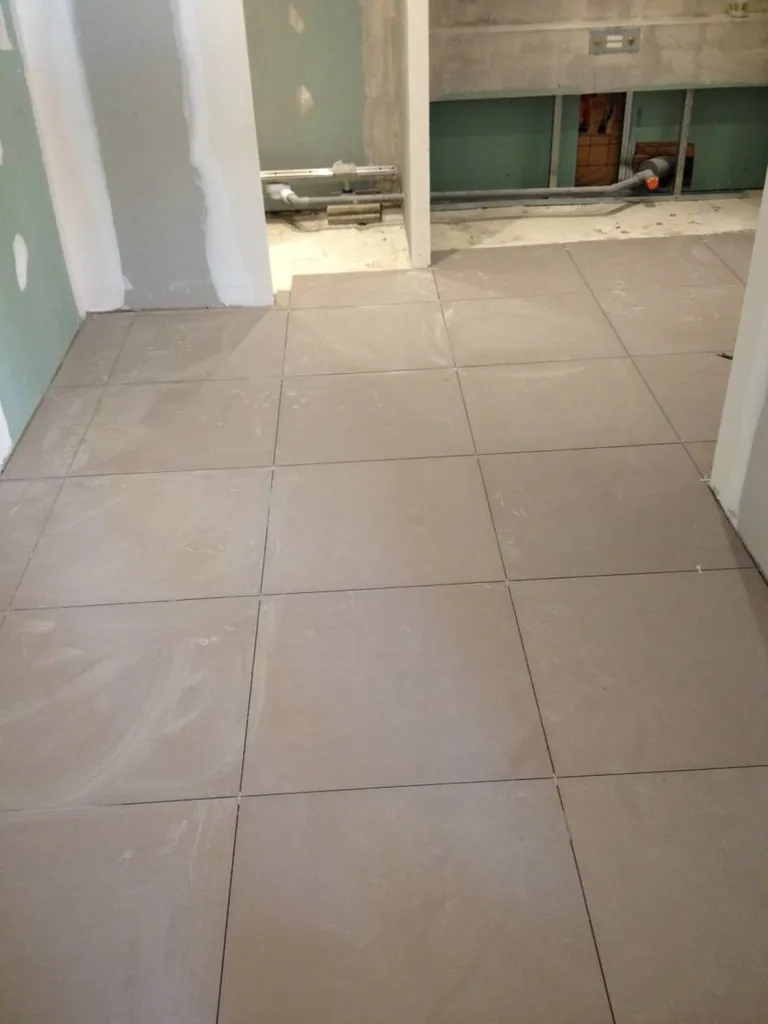 Pose du carrelage au sol lors de la rénovation d’une salle de bain à Saint-Germain-au-Mont-d’Or (Rhône – 69) pour un rendu précis et durable