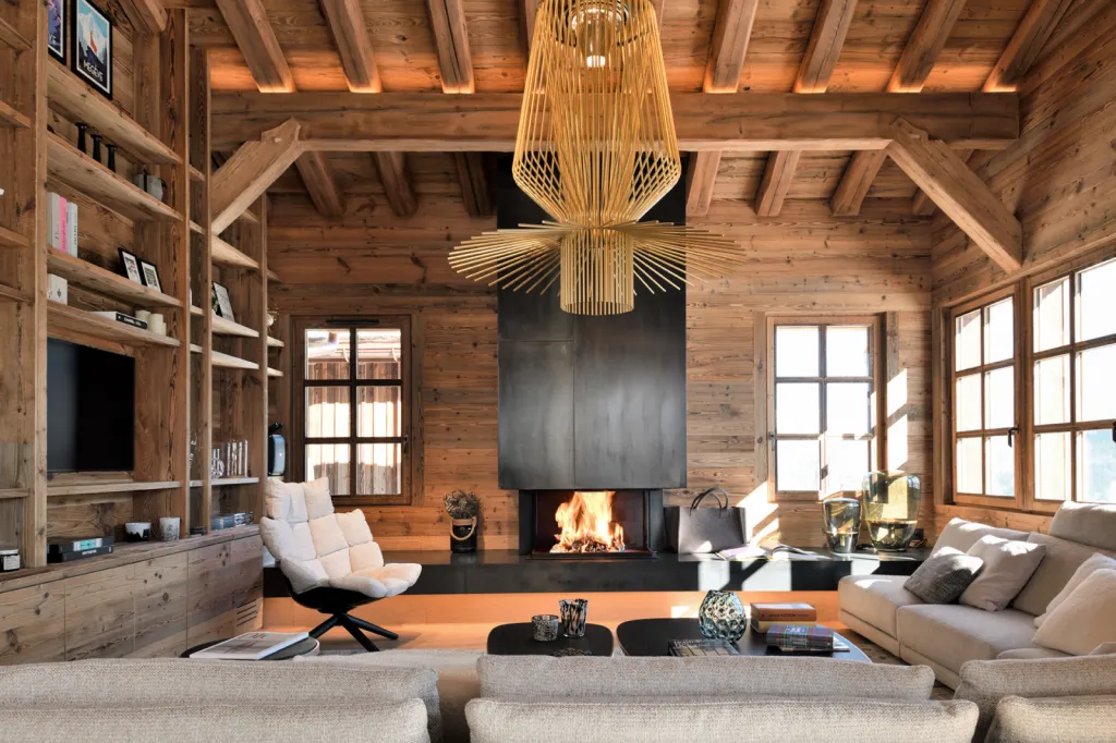 Création d’un espace coin feu en vieux bois à Megève entre charpente traditionnelle et bibliothèque sur mesure