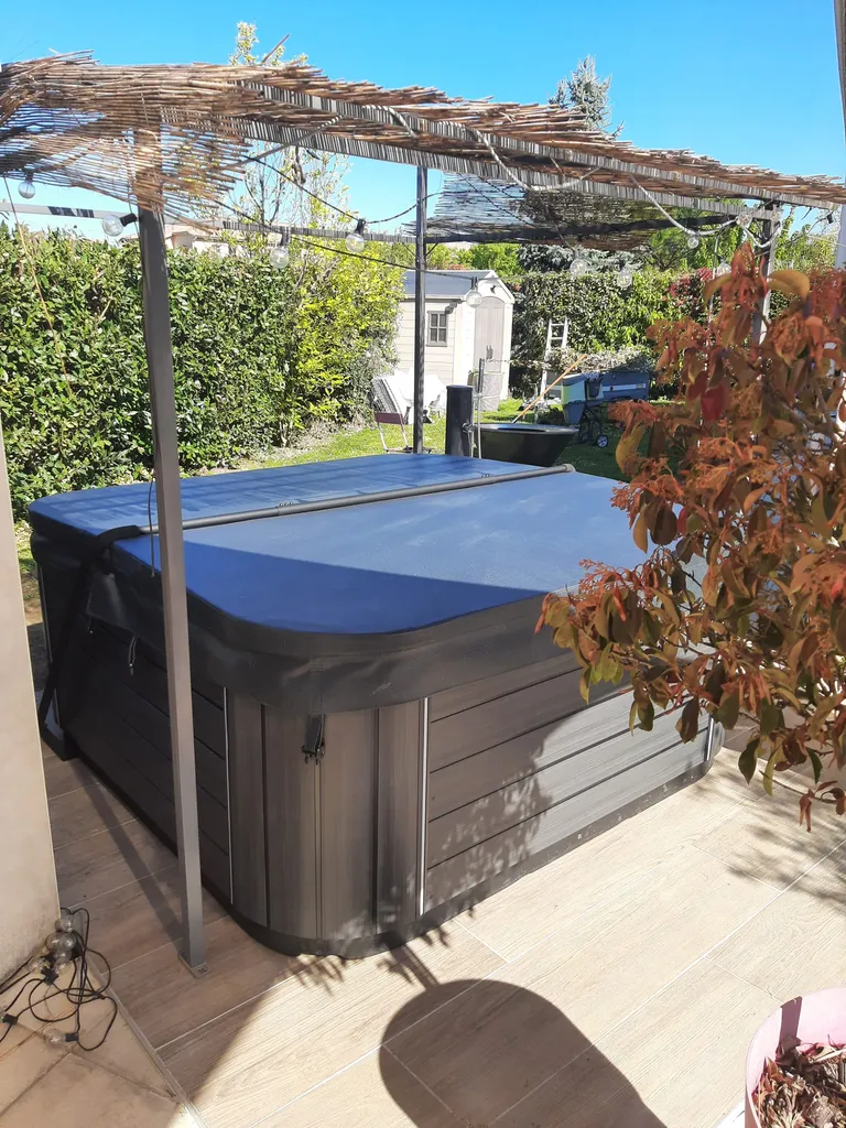 spa Jacuzzi S-550 en extérieur posé sous une pergolas avec sa couverture noire