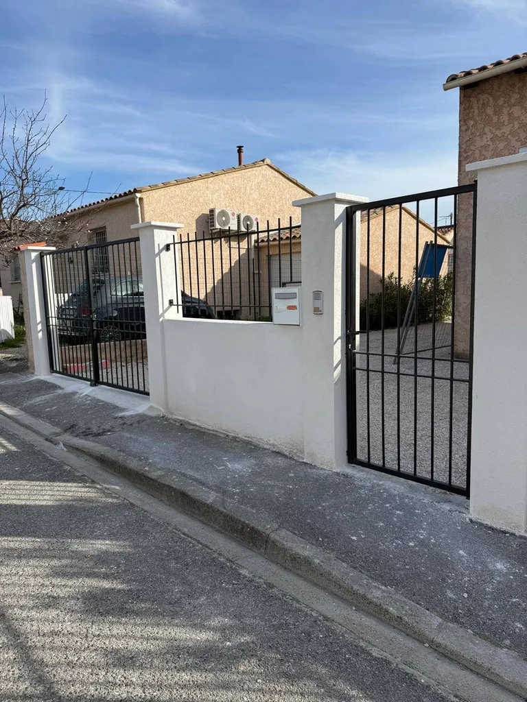 Vue de l'entrée principale sécurisée par une clôture en acier, combinant fonctionnalité et esthétique moderne à Calas Cabriès.