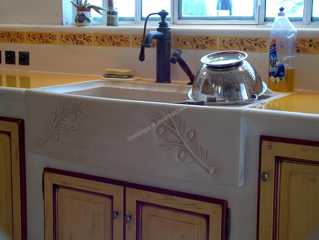 Evier en pierre massif, une cuve, un égouttoir et une sculpture de branche d'olivier sur la face.