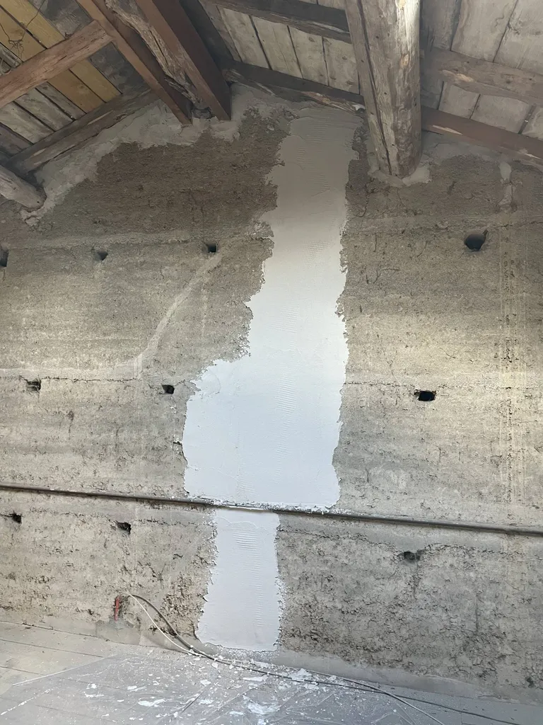 Rebouchage de fissures dans un mur en pisé pendant les travaux d'aménagement des combles à Gleizé près de Belleville en Beaujolais (69)