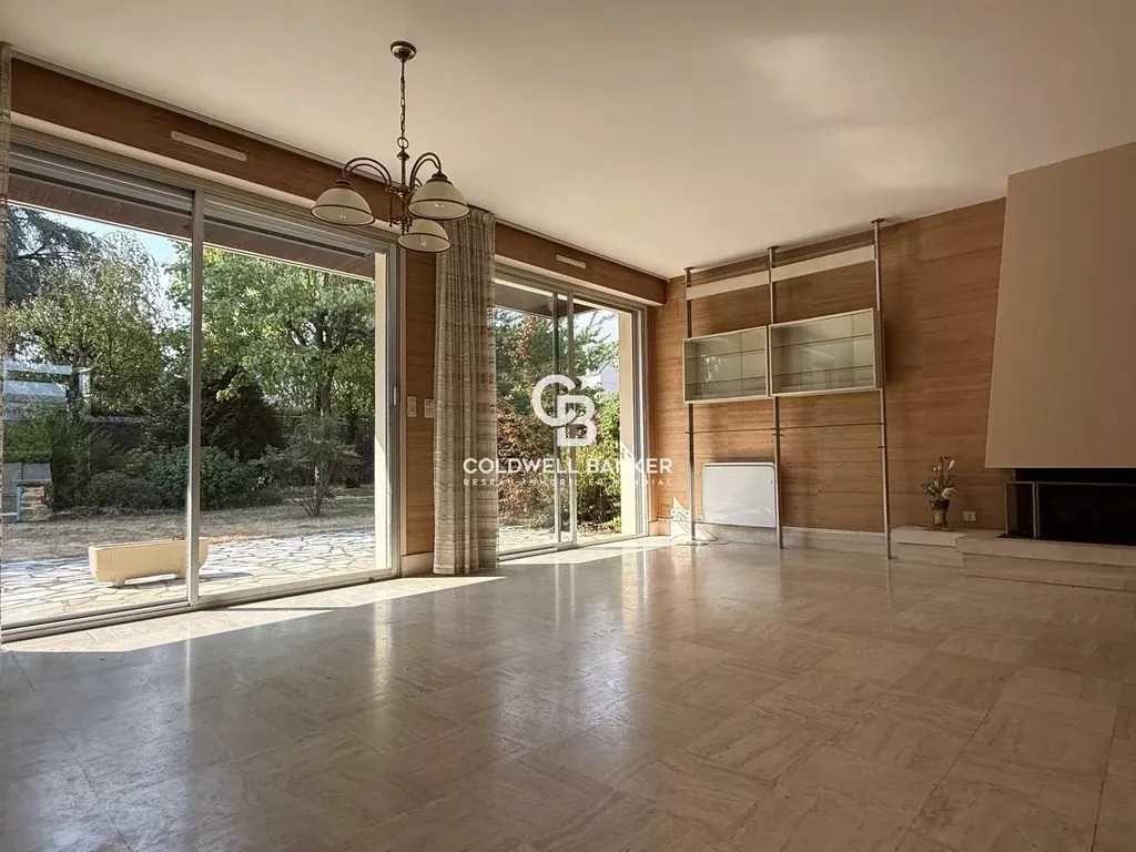 Grand salon avec cheminée et accès direct à la terrasse, dans cette propriété familiale de Laval.