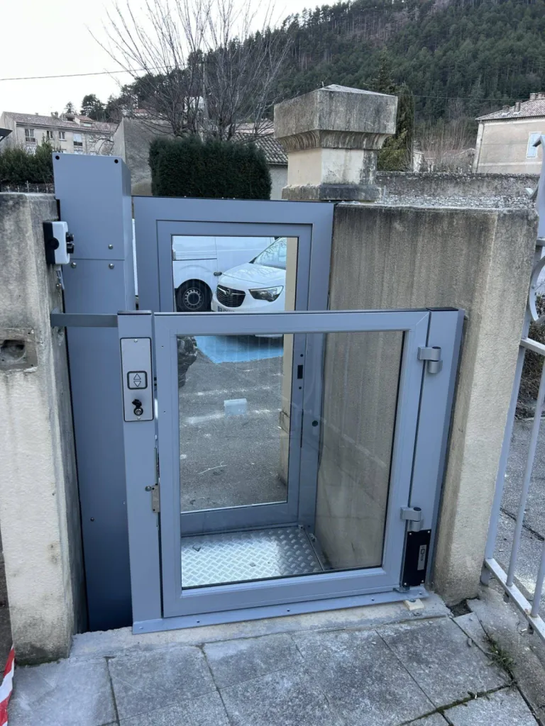 Accès R+1 via un portillon pour cette plateforme verticale en extérieur dans un ERP à Sisteron