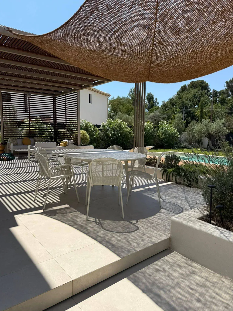 Ambiance chaleureuse et moderne sous une pergola artisanale conçue par l’Atelier du Ferronnier — l’élégance à la provençale.