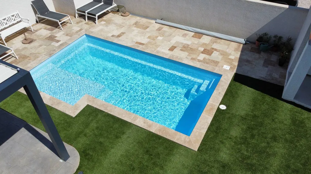Piscine dans jardin avec terrasse et pelouse