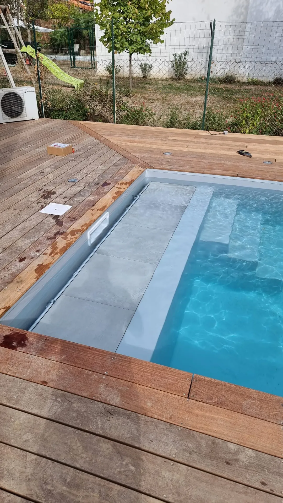 Une piscine traditionnelle intégrée au cœur d’un jardin toulousain sur mesure avec son volet roulant
