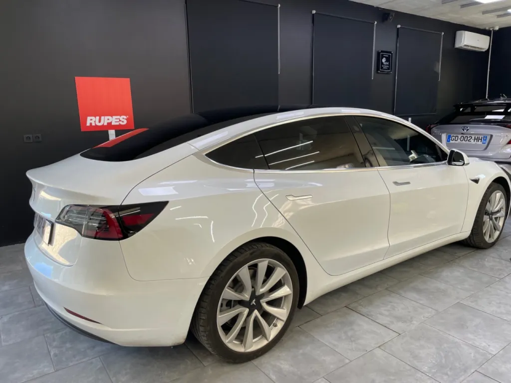 Pose d'un film solaire sur le vitrage de cette Tesla Model 3 à Antibes