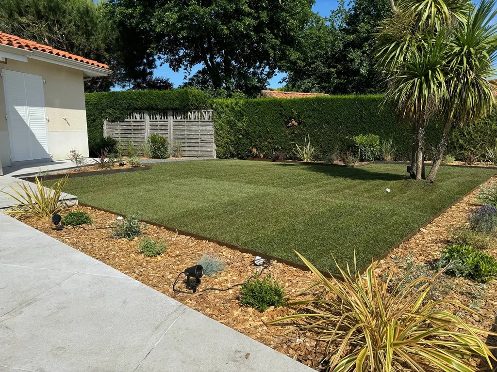 Pelouse d’un jardin changée en un espace esthétique et fonctionnel sur mesure près de Bias : gazon, massifs, et paillage