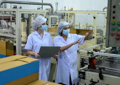 Managers qualité et production en discussion sur une ligne de conditionnement à Rungis – illustration de la coopération inter-fonctions dans l’industrie agroalimentaire pour fiabiliser la performance collective.