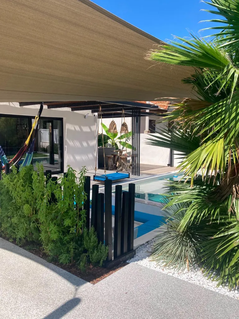 claustra de fers verticaux sous une pergola acier et bois, vue sur la piscine