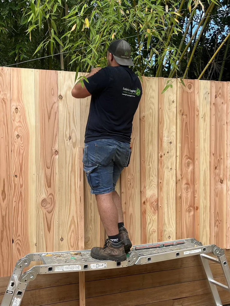 Clôture en lames de bois exotique ipé de qualité et voliges en Douglas dans un jardin paysagé près de Mimizan