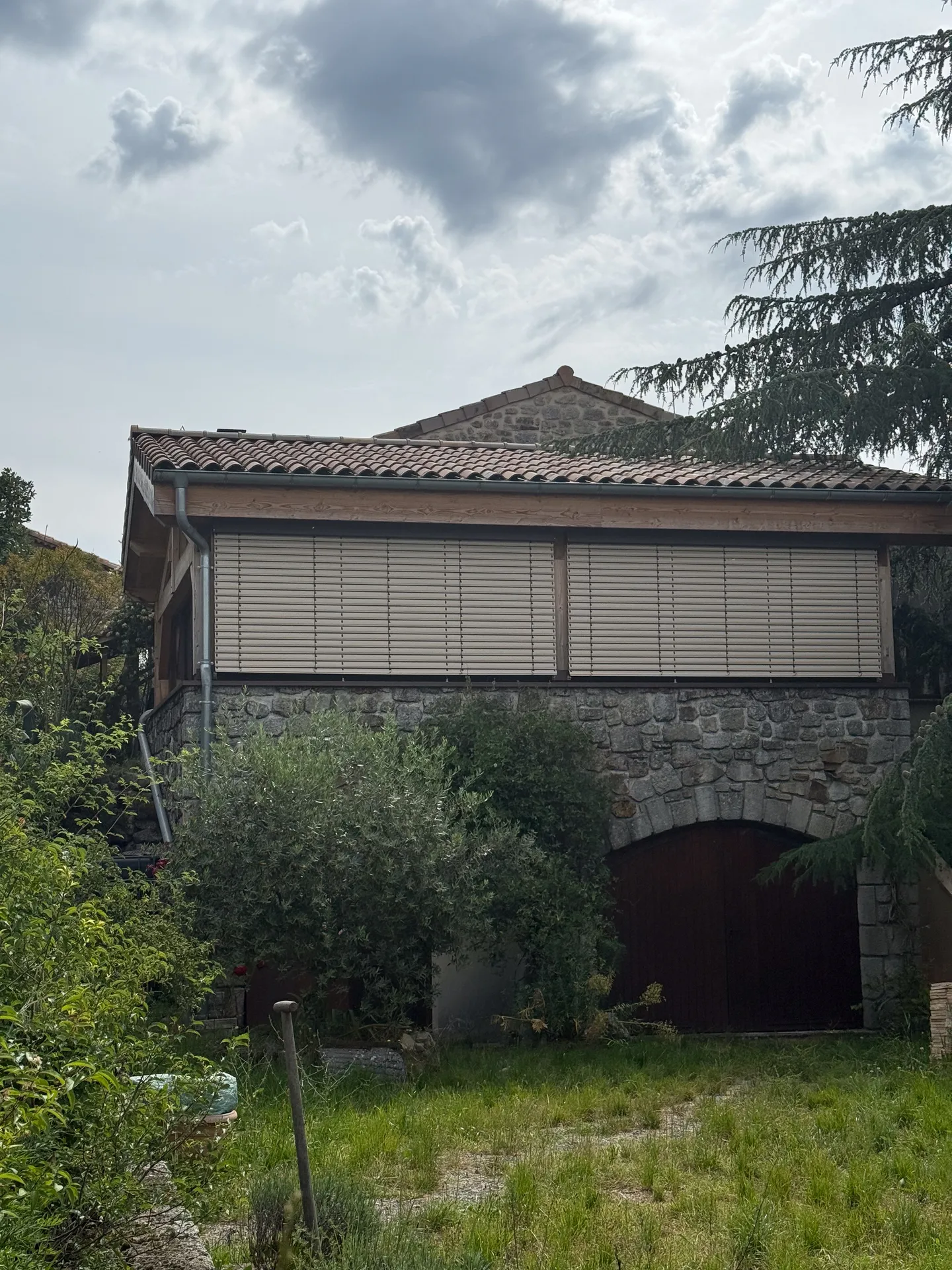 Fermeture d'une terrasse ardéchoise sous charpente bois avec de grands coulissants aluminium teinte rouille