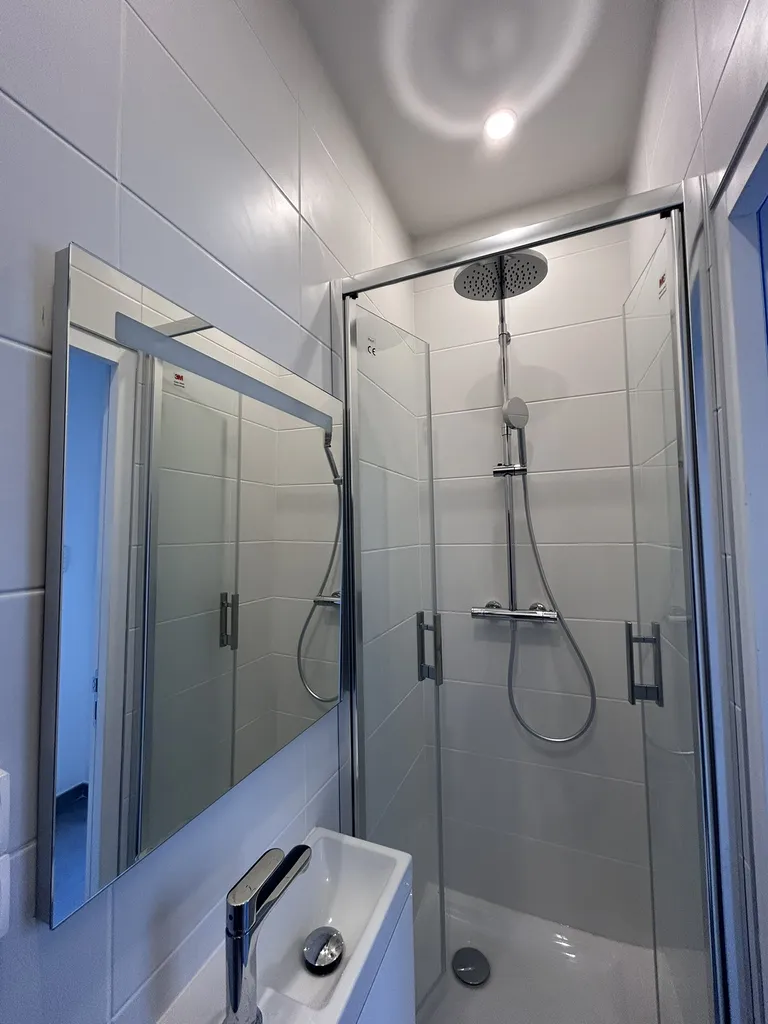 La salle d'eau métamorphosée avec un aménagement suspendu optimisé, un grand miroir à LED et des finitions en faïence contemporaine