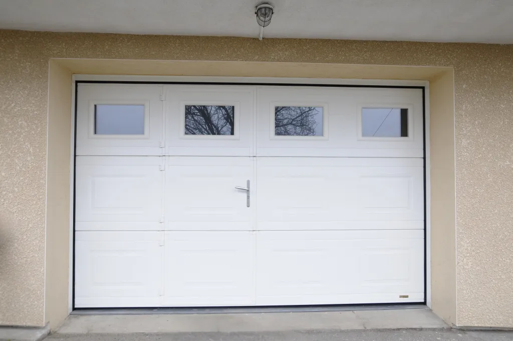Pose d'une porte de garage sectionnelle plafond avec porte de service intégrée et hublots sécurisés à Saint-Symphorien-sur-Coise dans les Monts du Lyonnais (69)