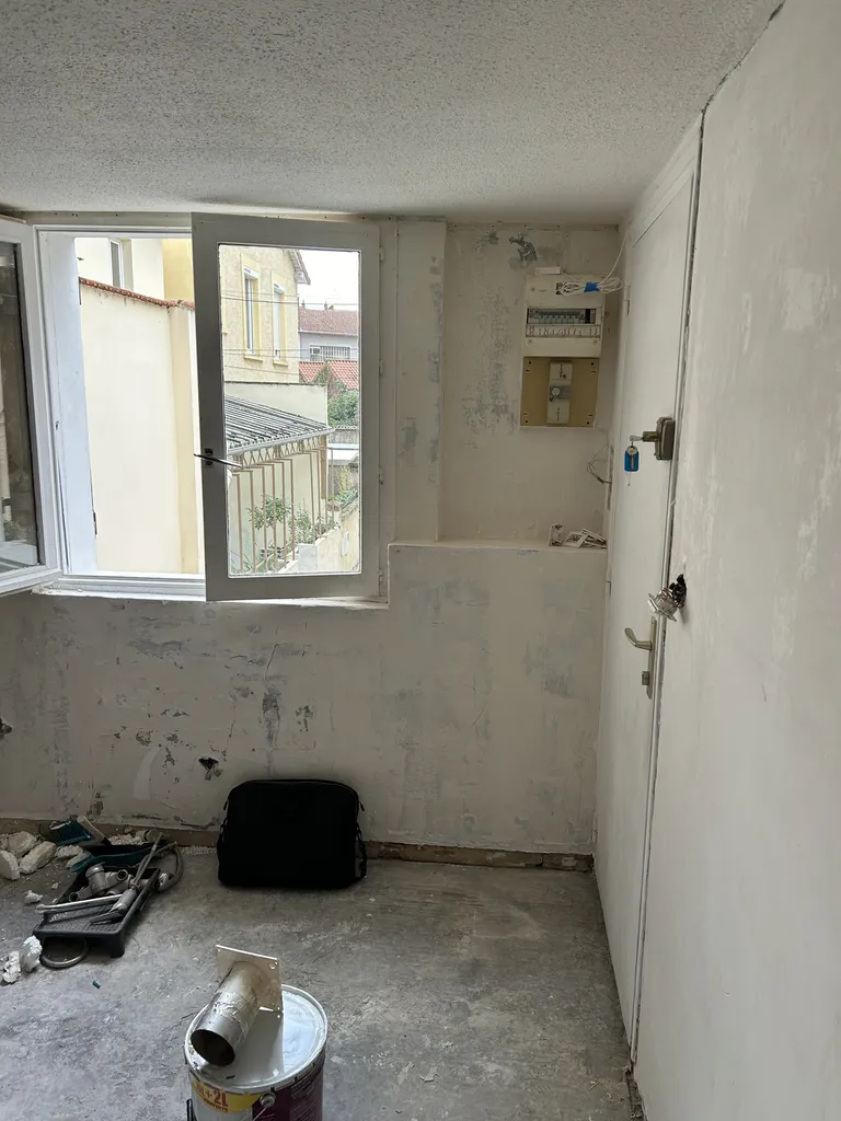 État initial de l'appartement classé DPE G à Lyon : un tableau électrique hors normes et des fenêtres vétustes en bois à simple vitrage, symboles d'une passoire thermique à rénover entièrement.