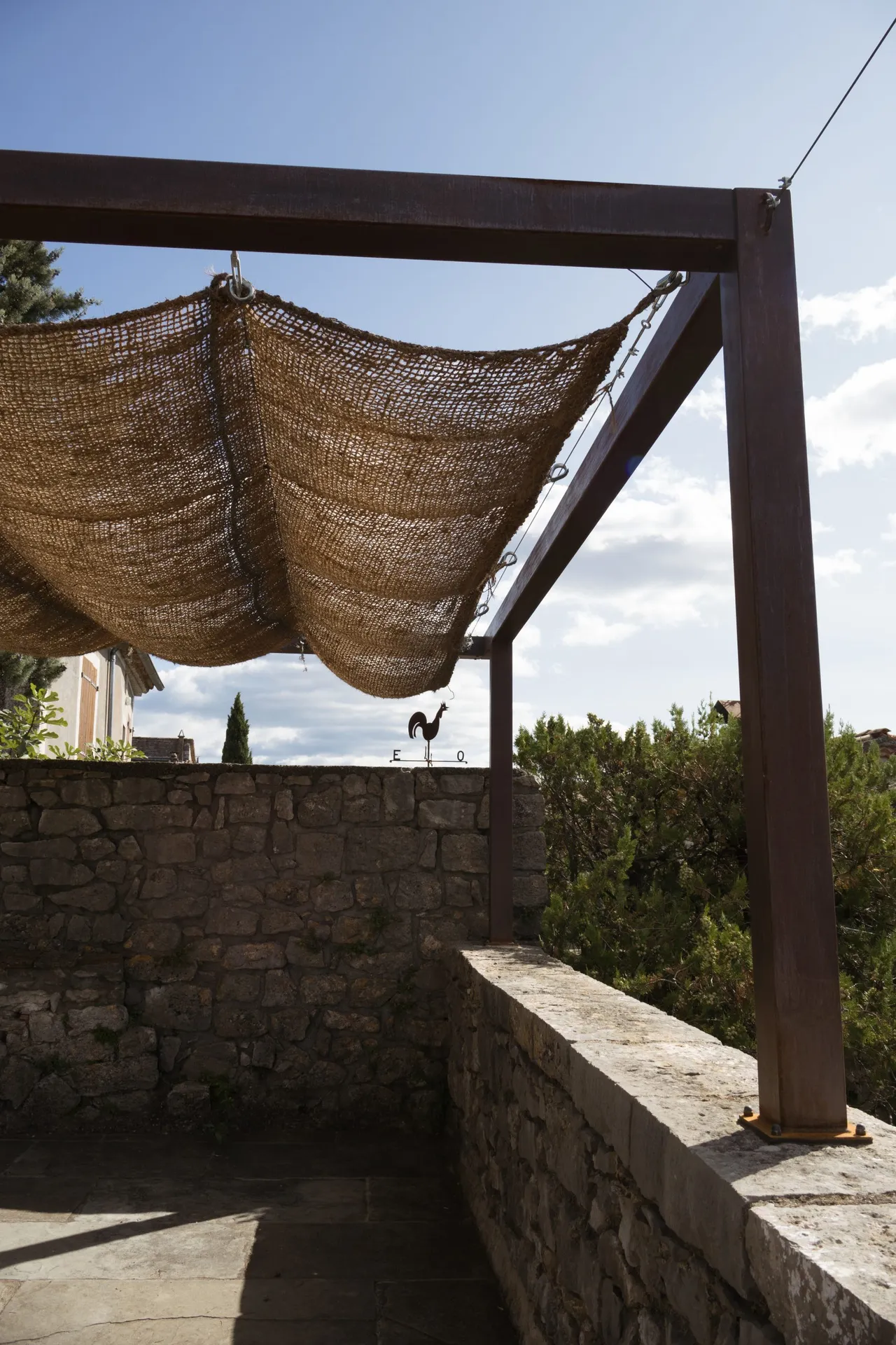 Pergola en fer effet rouille avec une toile de jute au château de balazuc pour une harmonie parfaite.