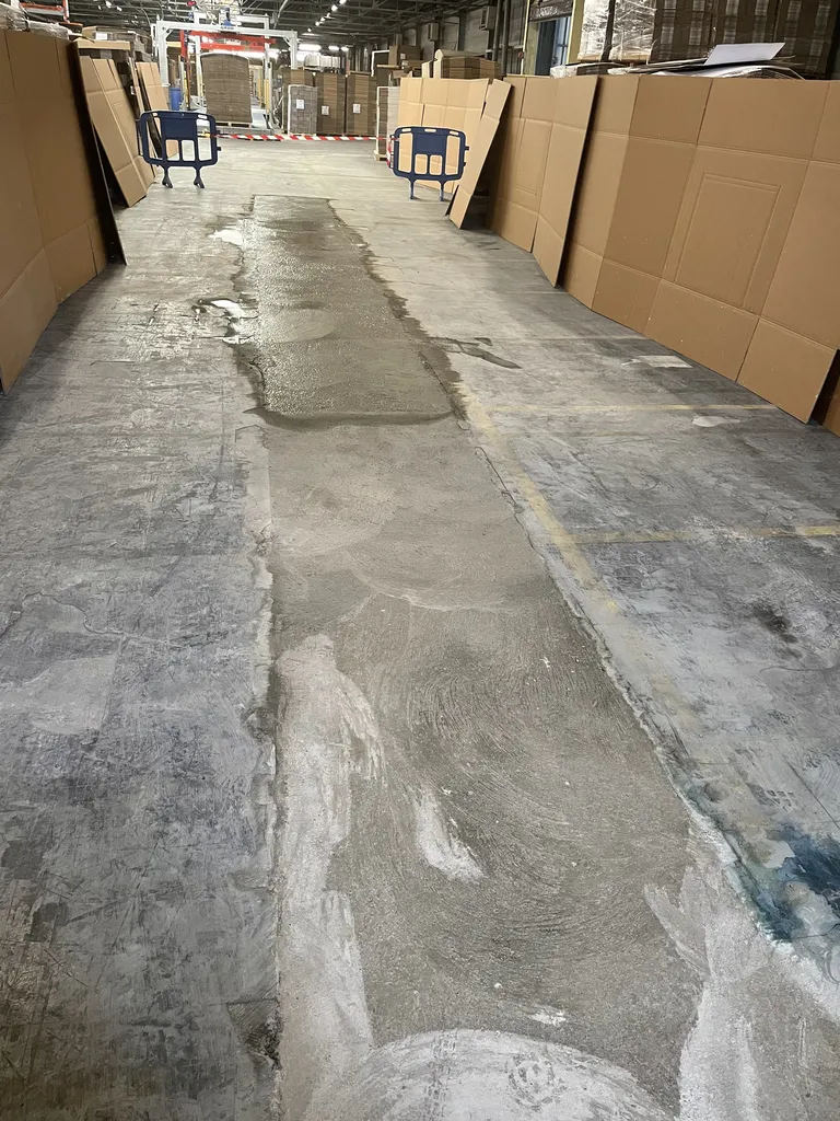 Sol en béton réparé après travaux dans un entrepôt à Belleville-en-Beaujolais (Rhône – 69), avec remise à niveau et finition talochée pour une circulation sécurisée des engins