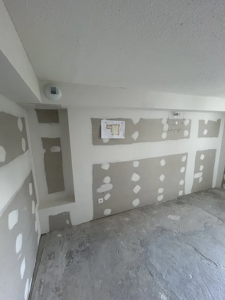 Finition des cloisons de doublage de la pièce principale en plaques de plâtre BA13 vissées sur fourrures après la validation de l'enveloppe thermique.