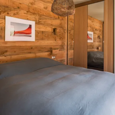 Chambre avec murs lambrissés en bois, rangements intégrés et décor doux, favorisant détente et convivialité, par l’Atelier D. architecte d'intérieur à Bordeaux.