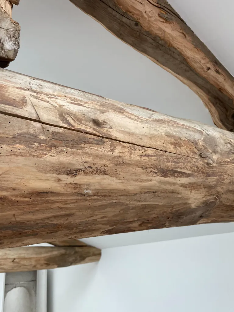 Poutres anciennes en chêne décapées par sablage dans des combles aménagés à Gleizé dans le Beaujolais, mettant en valeur le charme authentique de la charpente.