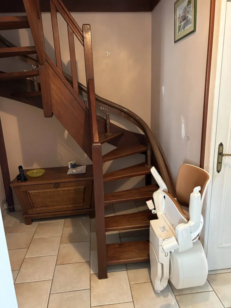 Une fois tout replié, voilà le faible espace occupé par ce fauteuil monte escalier OTOLIFT Modul'Air Smart en intérieur dans un escalier étroit 2/4 tournant à Marseille