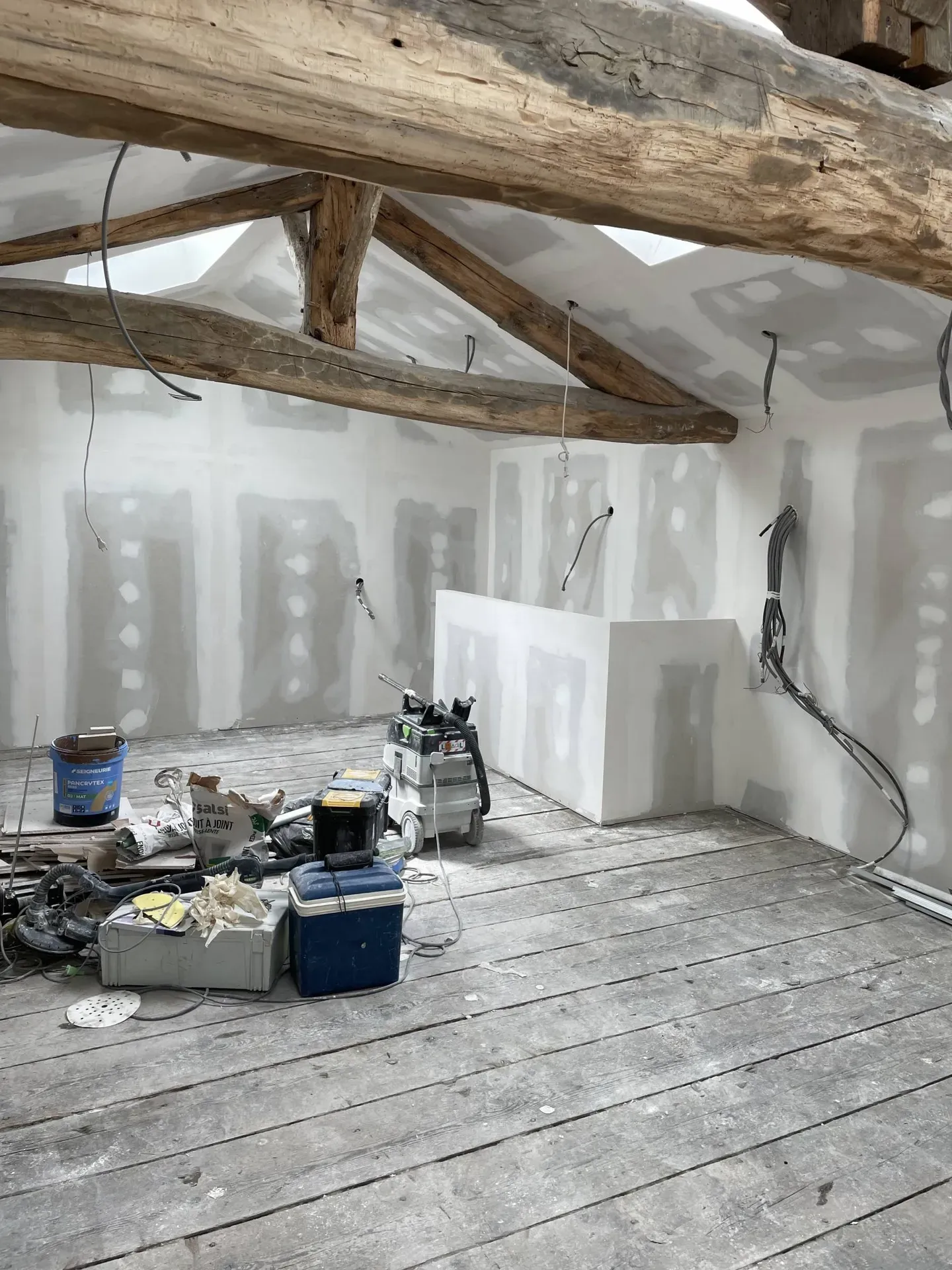 Pose de plaques de plâtre et réalisation des bandes à joints lors de l’aménagement des combles dans cette maison à Jassans-Riottier