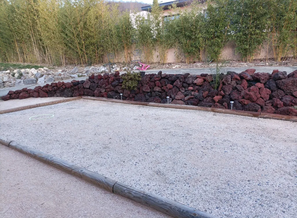 Enrochement pour soutènement avec pierre à bâtir en pouzzolane derrière un terrain de pétanque à Muret