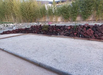 Enrochement pour soutènement avec pierre à bâtir en pouzzolane derrière un terrain de pétanque à Muret