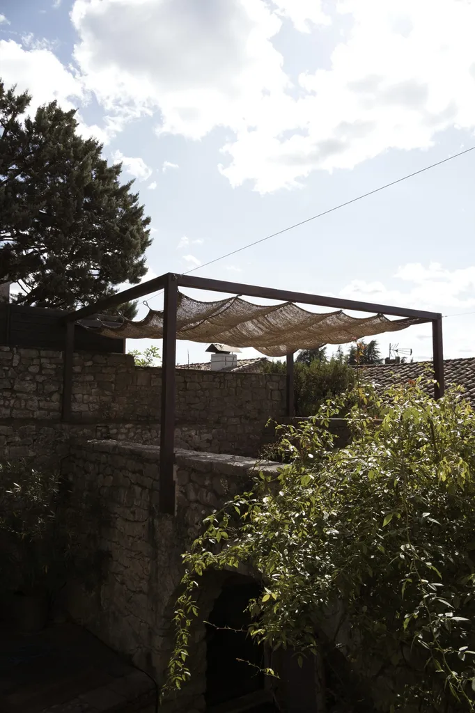 Pergola en fer effet rouille avec une toile de jute au château de balazuc pour une harmonie parfaite.