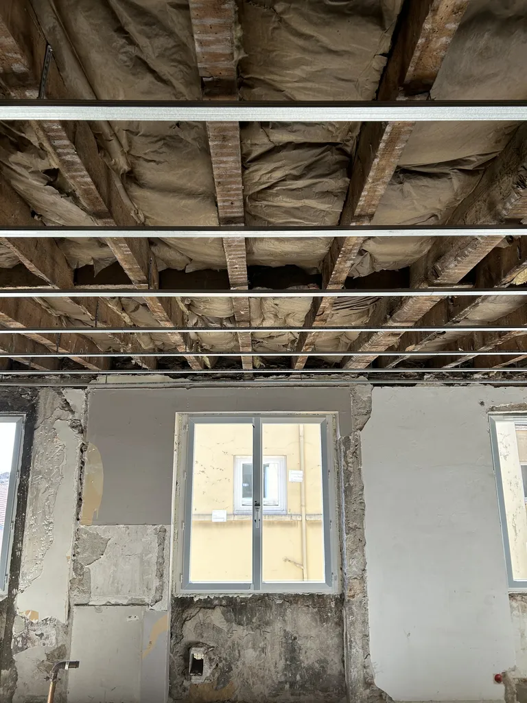 Première couche de laine de verre posée au plafond pour améliorer l’isolation thermique d’un appartement à Lyon (Rhône 69)