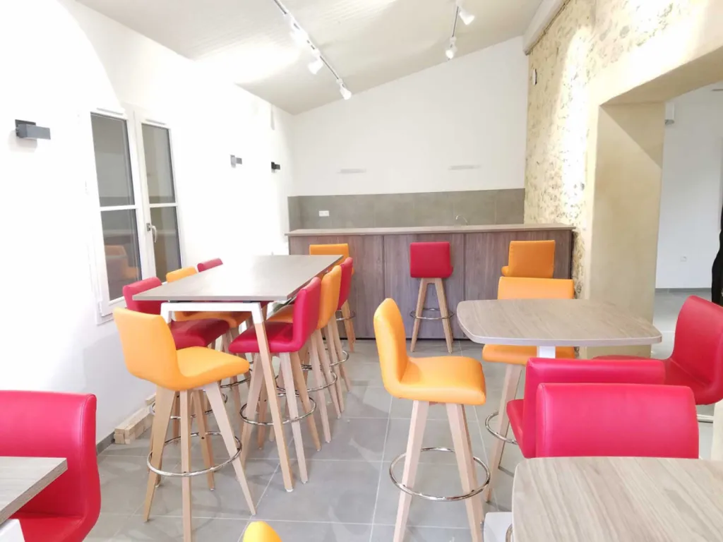 Réhabilitation de 200 m² de bureaux à Cheval-Blanc avec table de réunion 20 places, cafétéria colorée et design bois/blanc chaleureux