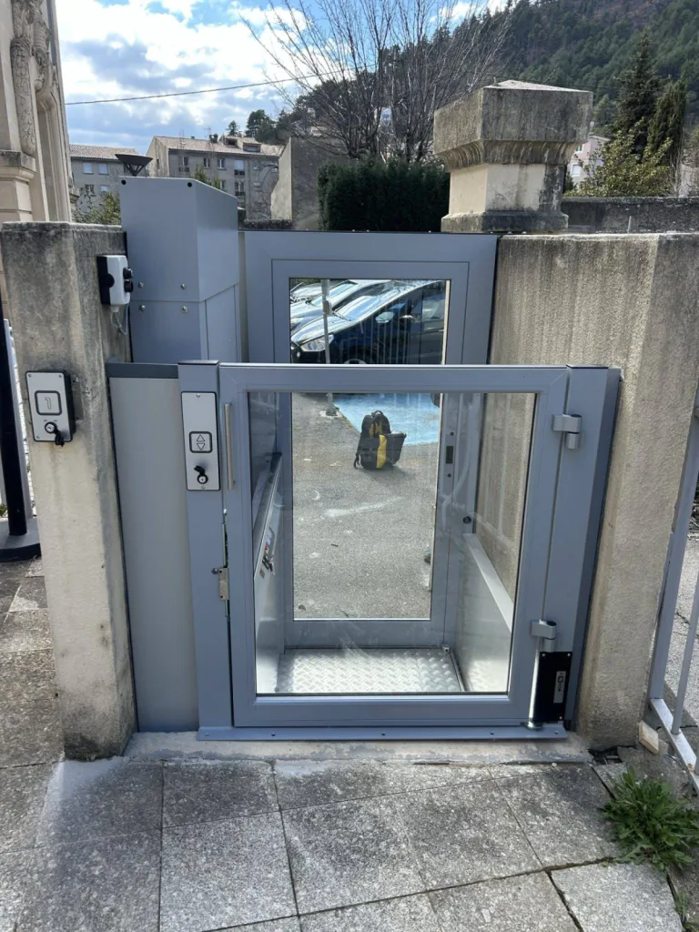 Les portes panoramiques dotées de verre transparent donne cette agréable sensation d'espace avec cette plateforme verticale en extérieur dans un ERP à Sisteron