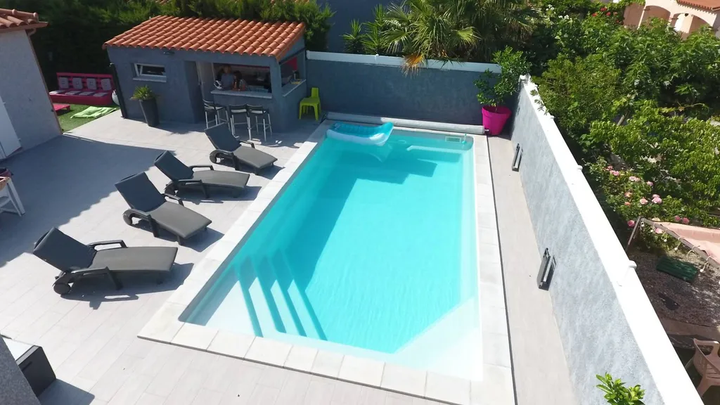Piscine vue biais sur terrasse avec transats