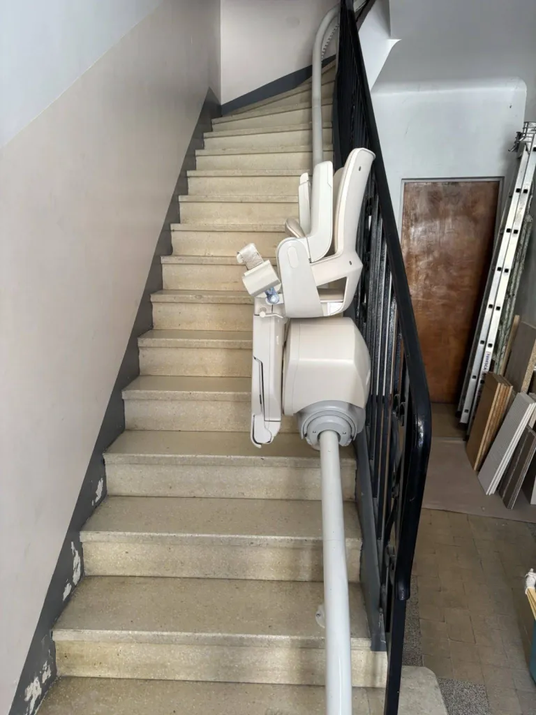 Le fauteuil monte escalier OTOLIFT SMART sur son point de charge pour dégager l'accès à l'escalier de la copropriété entre Marseille et Toulon