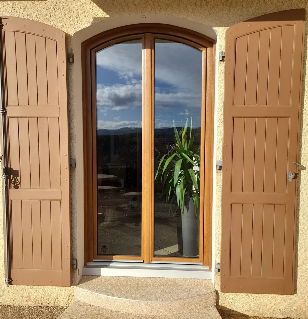 Rénovation menuiserie cintrée avec une porte-fenêtre deux vantaux en PVC de la marque Bouvet, coloris imitation bois chêne liège de 215 x 140 cm à Roanne dans la Loire (42)