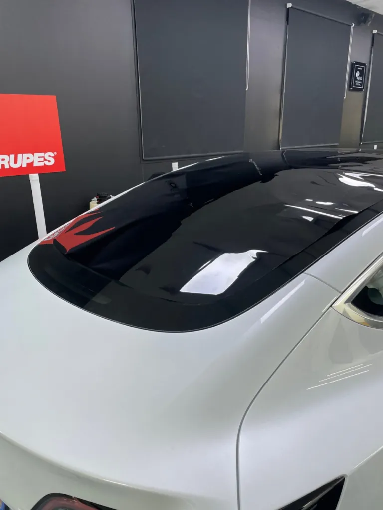 Pose d'un film solaire sur le vitrage de cette Tesla Model 3 à Antibes