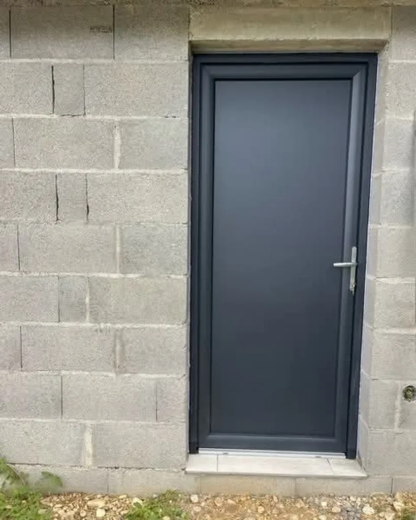 Installation d'une porte de service dans un garage en pvc gris anthracite avec serrure se sécurité et panneau plein à Saint Jean des Vignes