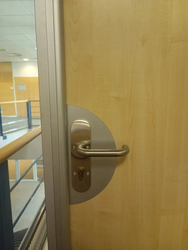 Installation d'une serrure Kel Abloy sur une porte en bois avec mortaisage de la porte pour encastrement de la serrure dans une usine de la Plaine de l'Ain à Lagnieu