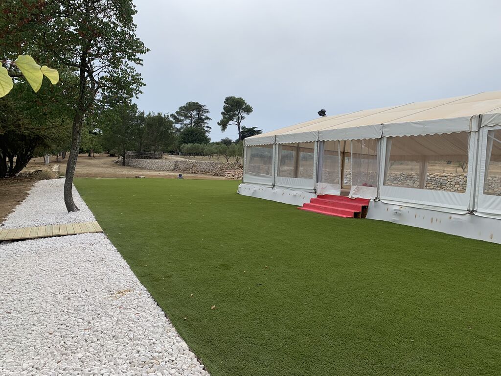 Installation complète de gazon synthétique haut de gamme autour d’un chapiteau pour réceptions et mariages à Lourmarin