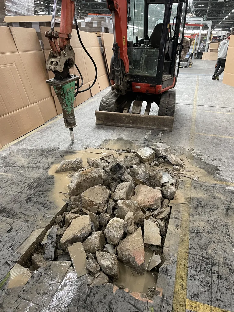 Utilisation d’un brise-roche pour casser la partie endommagée du sol en béton avant sa réparation dans un entrepôt à Belleville-en-Beaujolais (Rhône – 69)