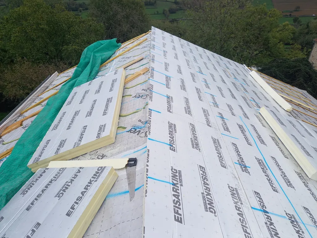 Isolation de toiture par sarking permettant de limiter les déperditions de chaleur et améliorer le confort thermique d’une maison en pierre à Beaujeu
