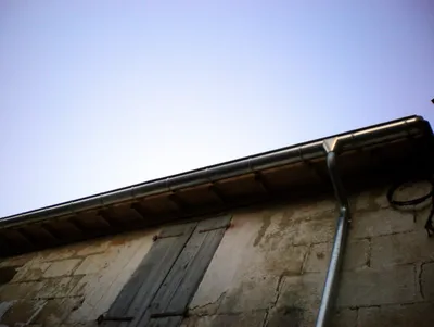 Installation de gouttières en zinc pour l'évacuation efficace des eaux pluviales sur une toiture traditionnelle de maison