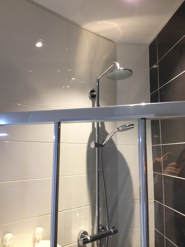 Paroi de douche coulissante en verre traité anti-calcaire avec profilé aluminium satiné dans une salle de bains rénovée à Lyon (Rhône – 69)
