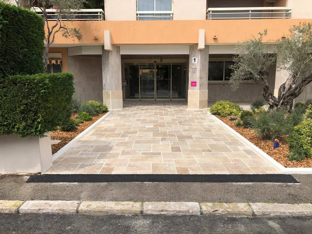 Entrée rénovée à Nice avec travertin et massifs fleuris
