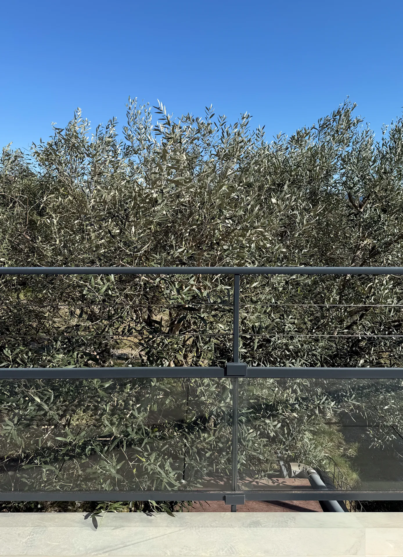 La finesse d’un garde-corps mêlant verre, câbles inox et aluminium pour ouvrir la terrasse sur le paysage