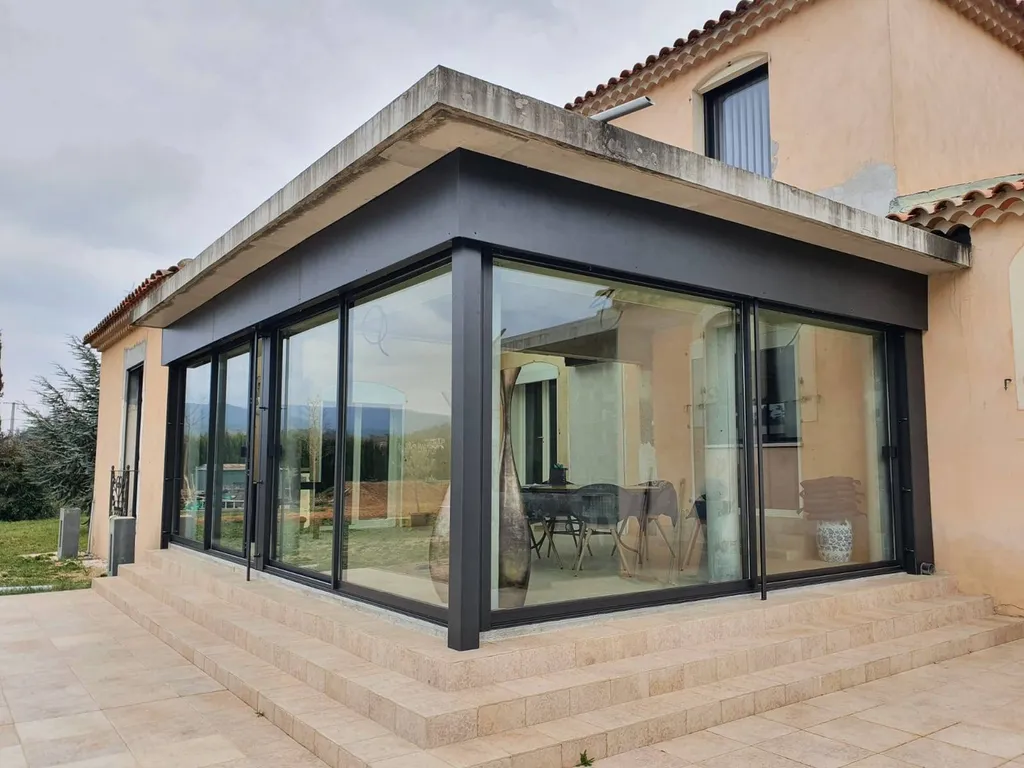 Installation d'une belle véranda en aluminium de la marque Technal de couleur noire près de Mimet