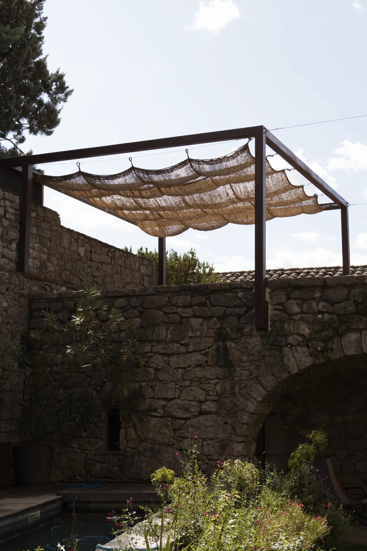 Pergola en fer effet rouille avec une toile de jute au château de balazuc pour une harmonie parfaite.